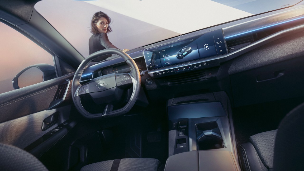 Close-up van het pure panel display-systeem in een nieuwe Opel Grandland met een vrouw die op een wagen leunt en naar binnen kijkt